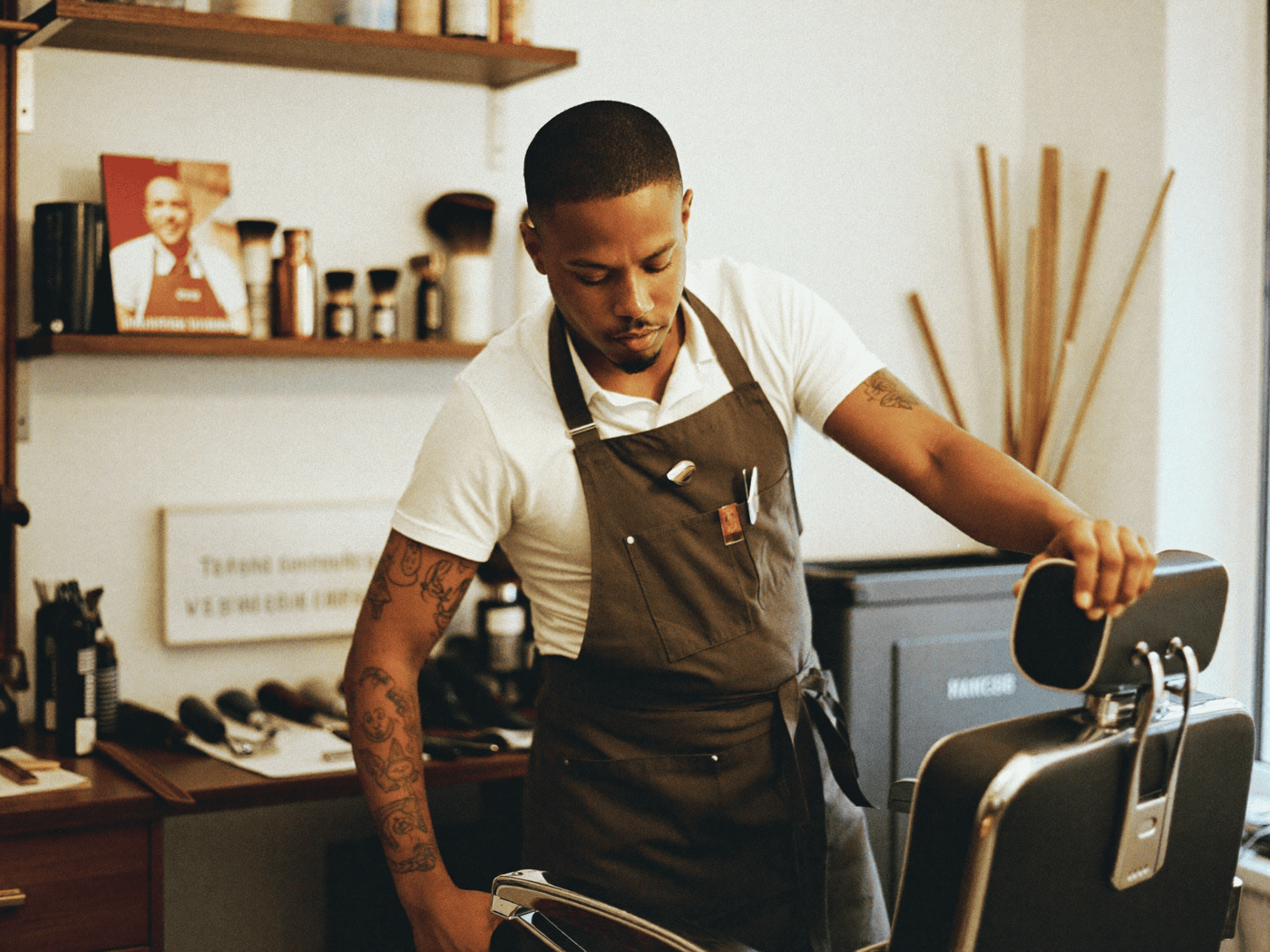 A barber adjusting his own hours and settings on a tablet at the chair