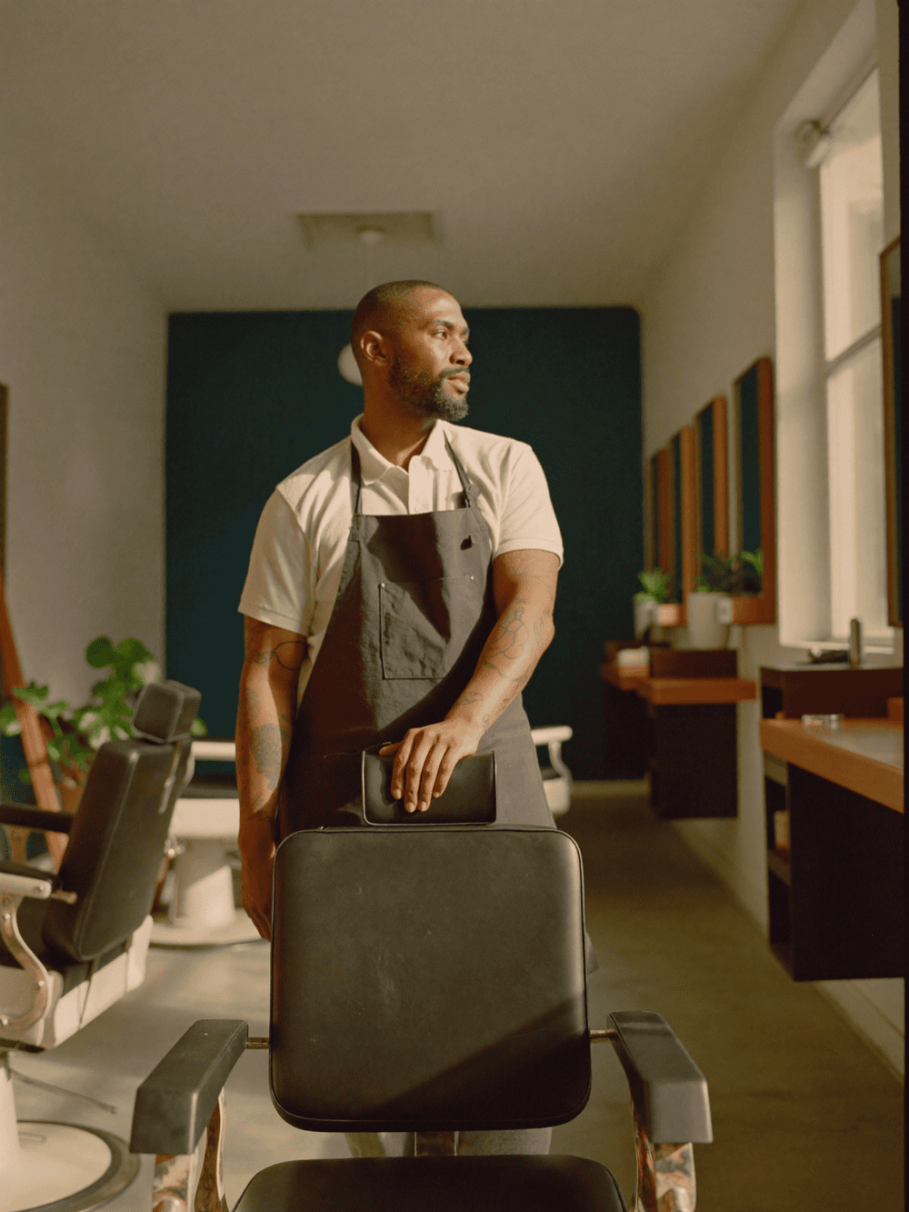 A barbershop owner unlocking his own shop at dawn, lights coming on one by one